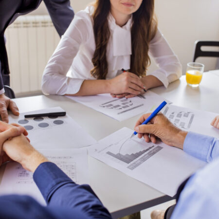 close-up-mature-businessman-analyzing-graph-with-his-colleagues