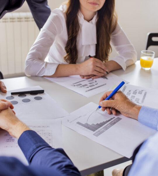 close-up-mature-businessman-analyzing-graph-with-his-colleagues