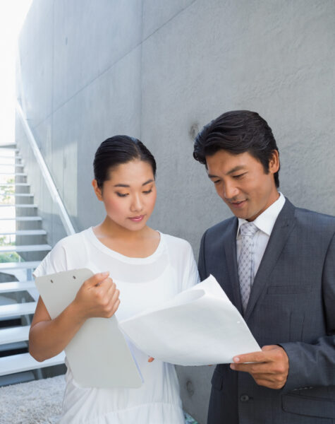 Estate agent showing lease to customer and smiling outside a house