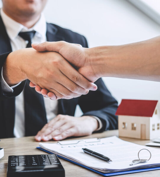 Finishing to successful deal of real estate, Broker and client shaking hands after signing contract approved application form, concerning mortgage loan offer for and house insurance.