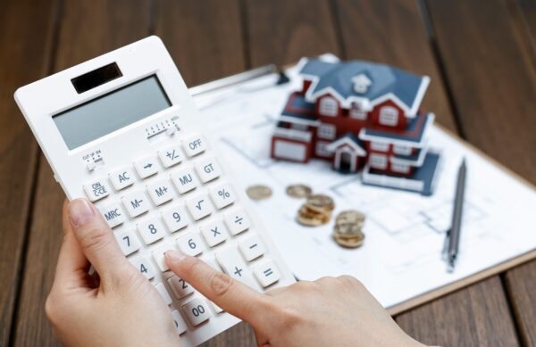 une-main-feminine-exploitant-une-calculatrice-devant-un-modele-de-maison-de-villa (1)