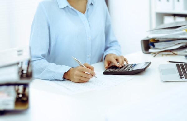Professionnelle vérifiant des documents comptables avec une calculatrice