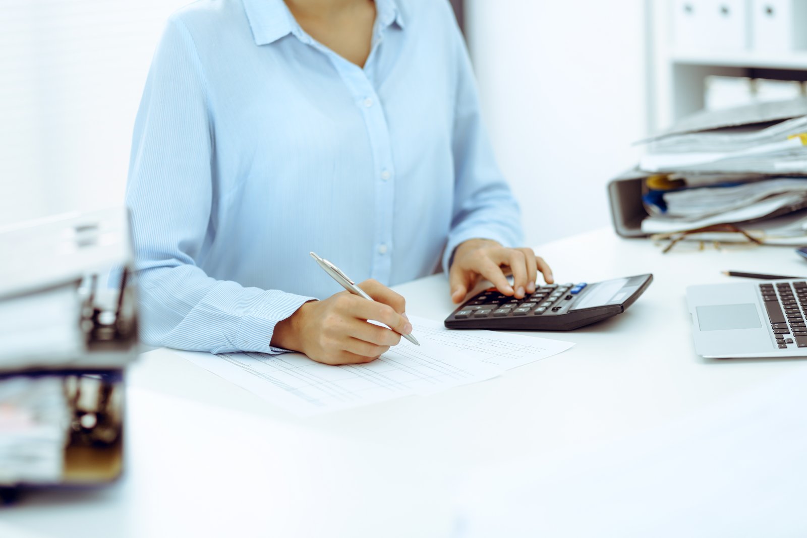 Professionnelle vérifiant des documents comptables avec une calculatrice